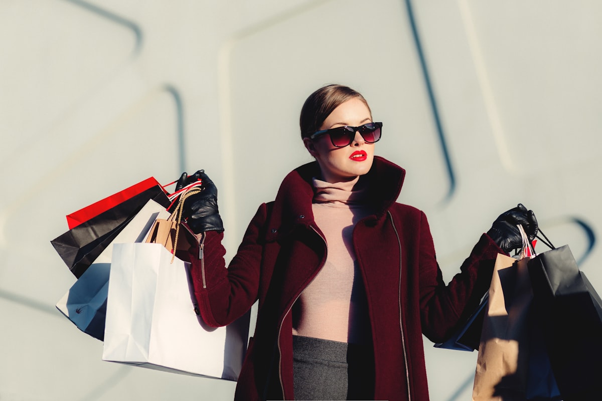 Woman in a tailored coat carrying shopping bags on a city street